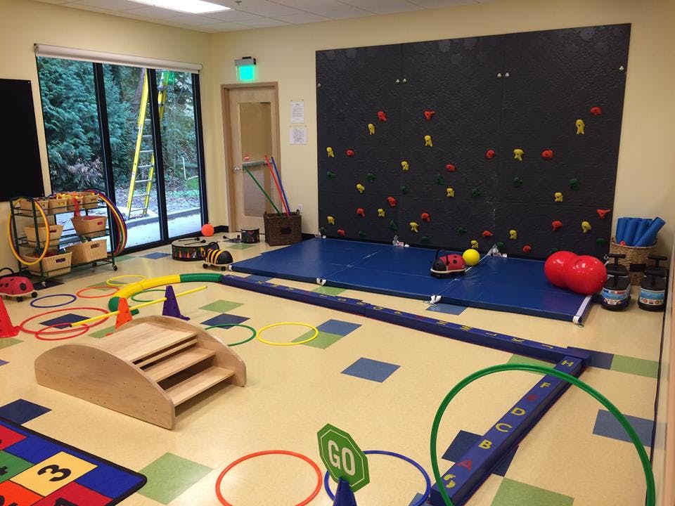 Indoor play area with climbing wall, mats, and various play equipment