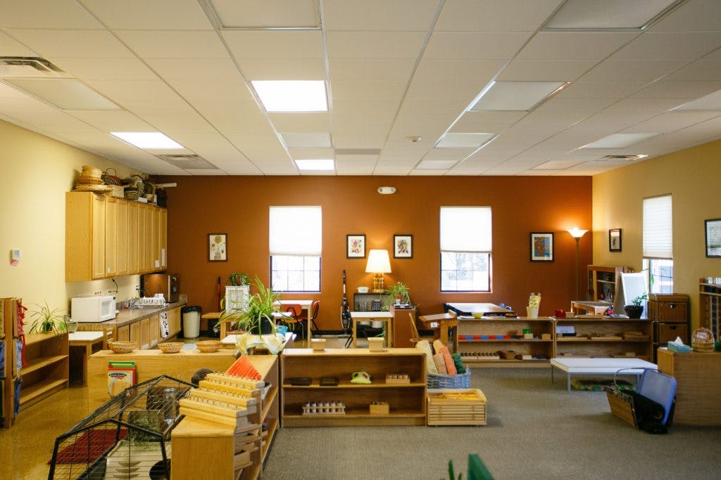 Classroom with wooden shelves, tables, and a counter area