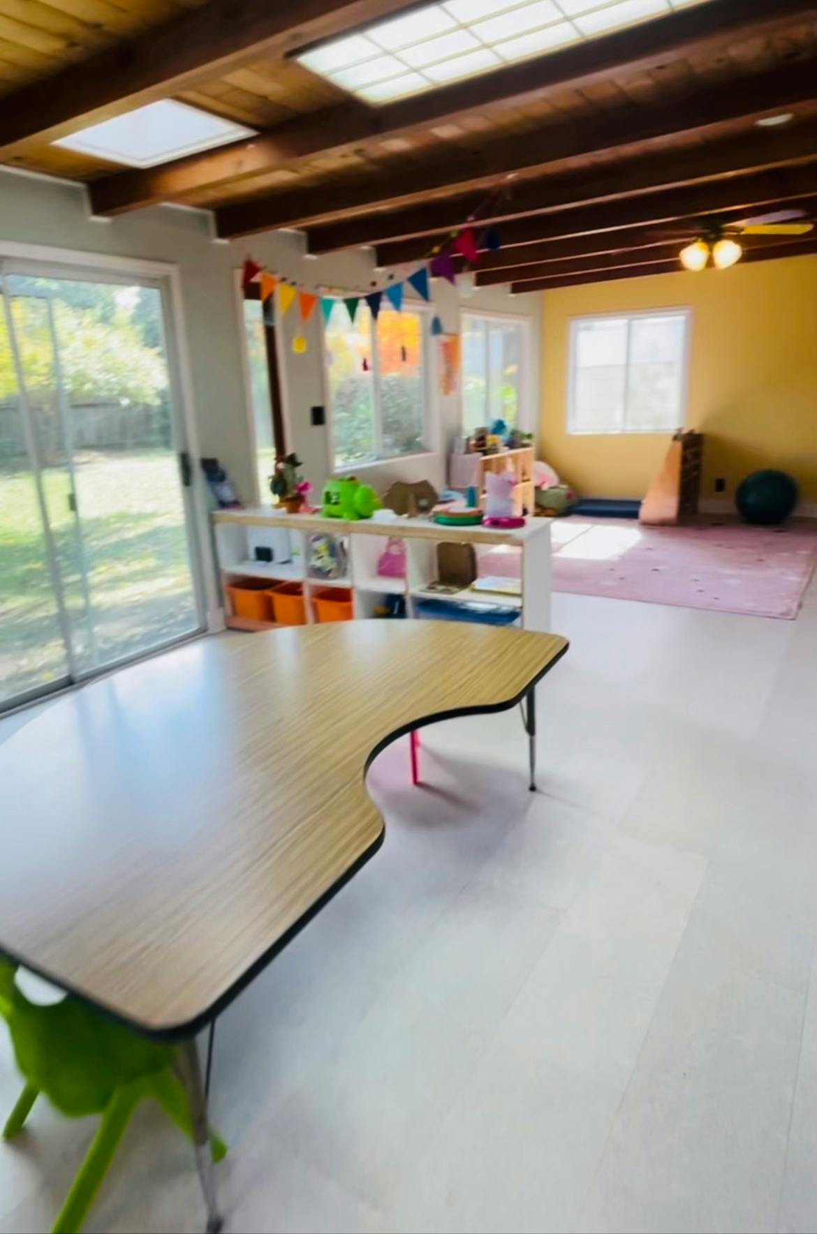 Classroom with a light wood table and green chair in the foreground