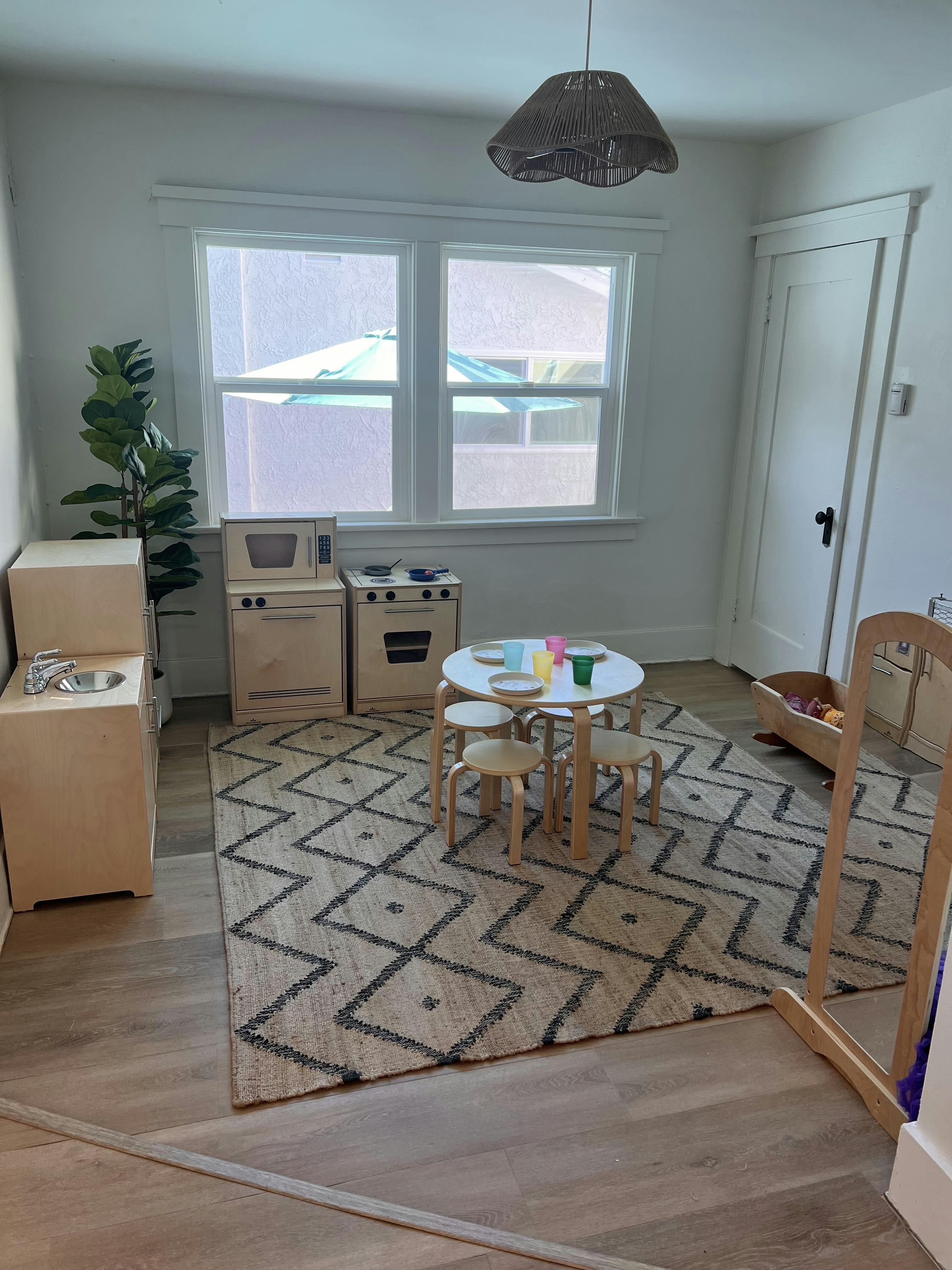 Playroom with toy kitchen, small table and stools, and patterned rug
