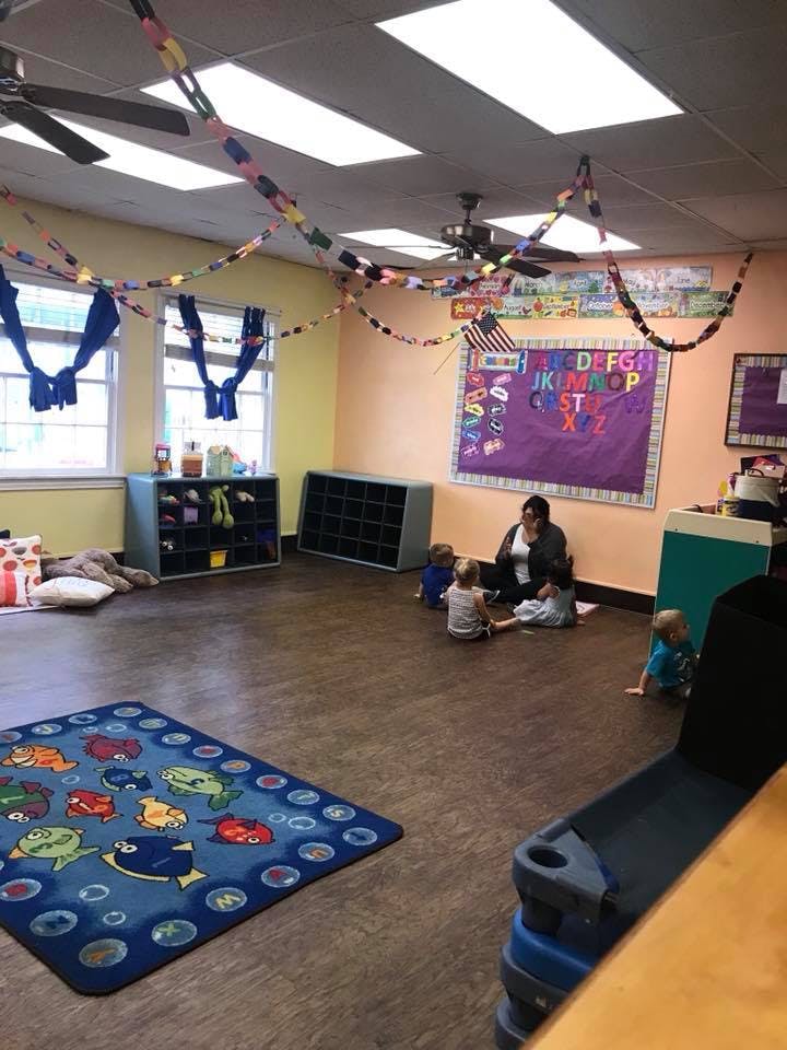 Adult and children sitting on the floor in a classroom