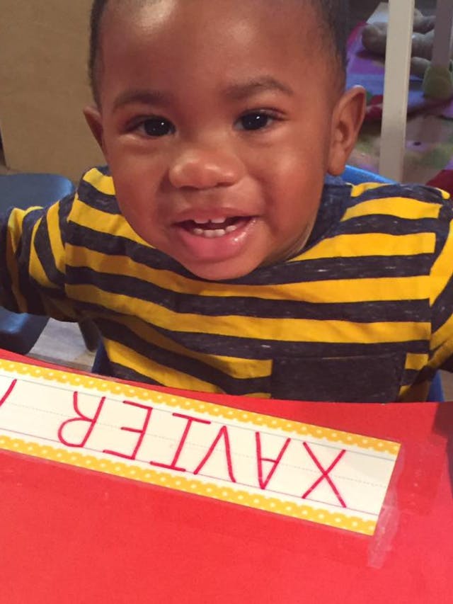 Child in striped shirt at a table with a name tag that reads "XAVIER"