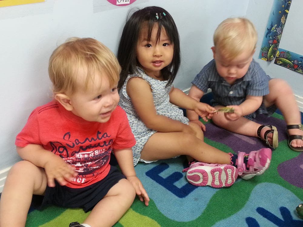 Three children sitting on a colorful rug