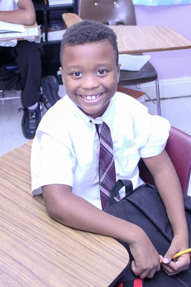 Child in a classroom smiling at the camera
