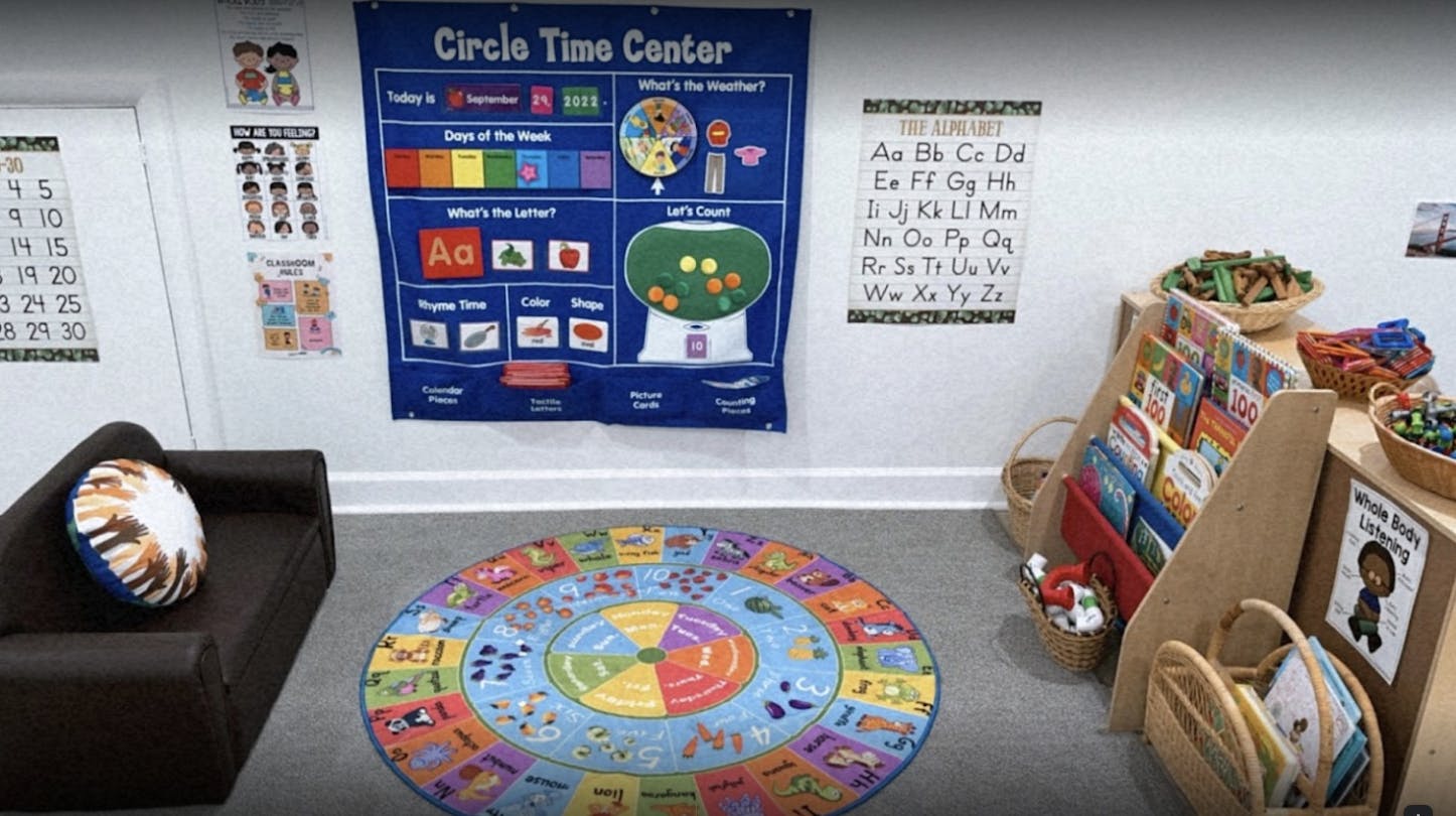 Classroom with a colorful rug, couch, and educational posters on the wall