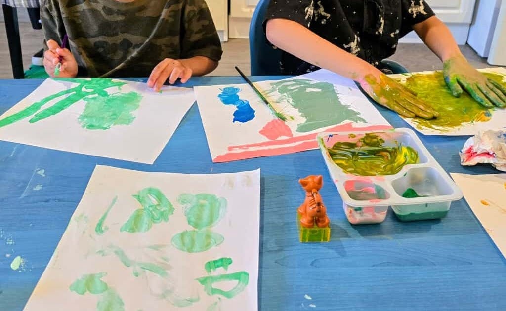 Children painting with hands and brushes on paper