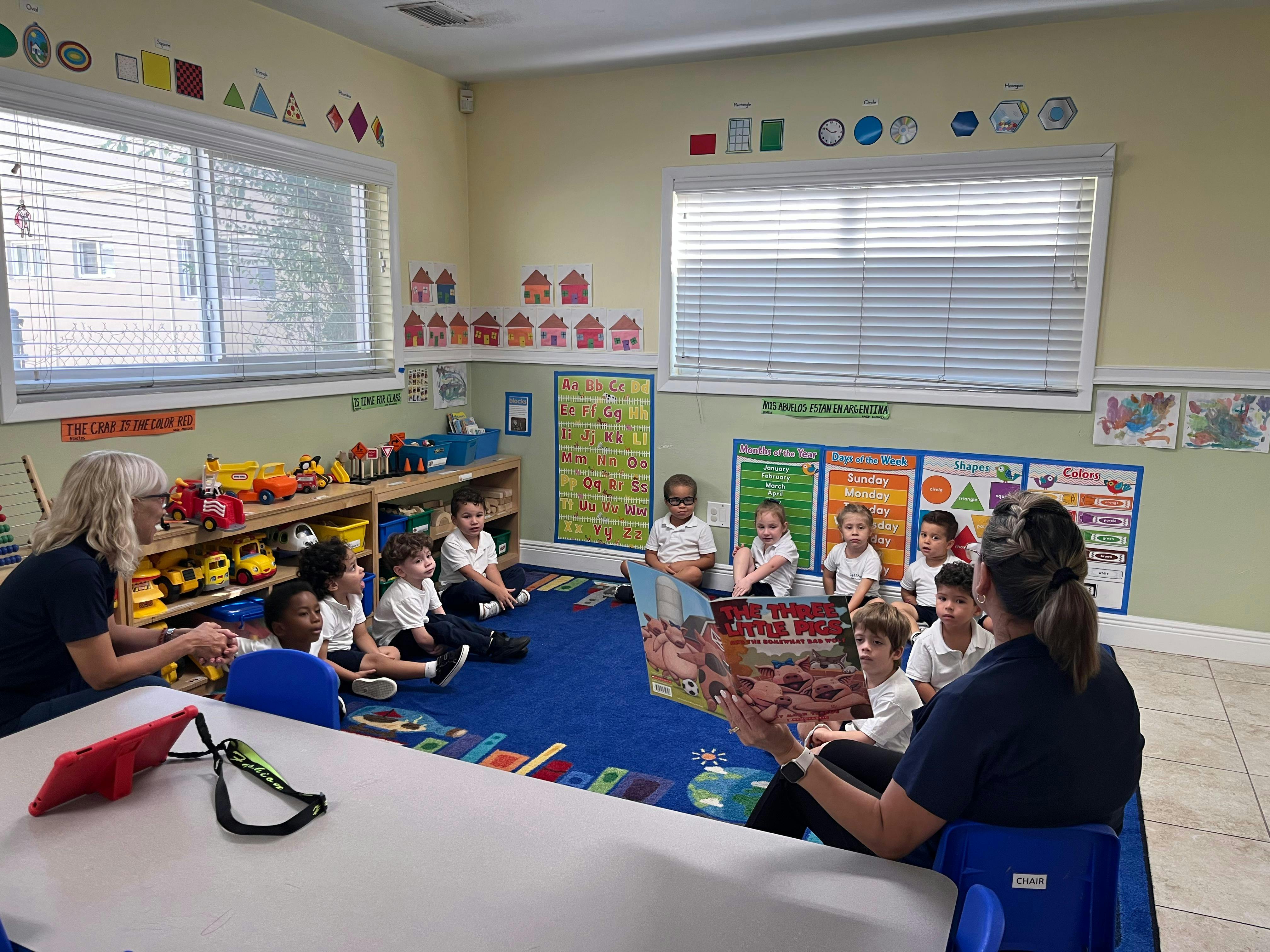 Adult reading a book to a group of children in a classroom