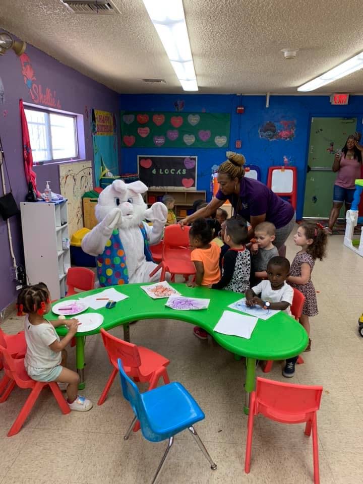 Person in bunny costume with children and adult in a classroom