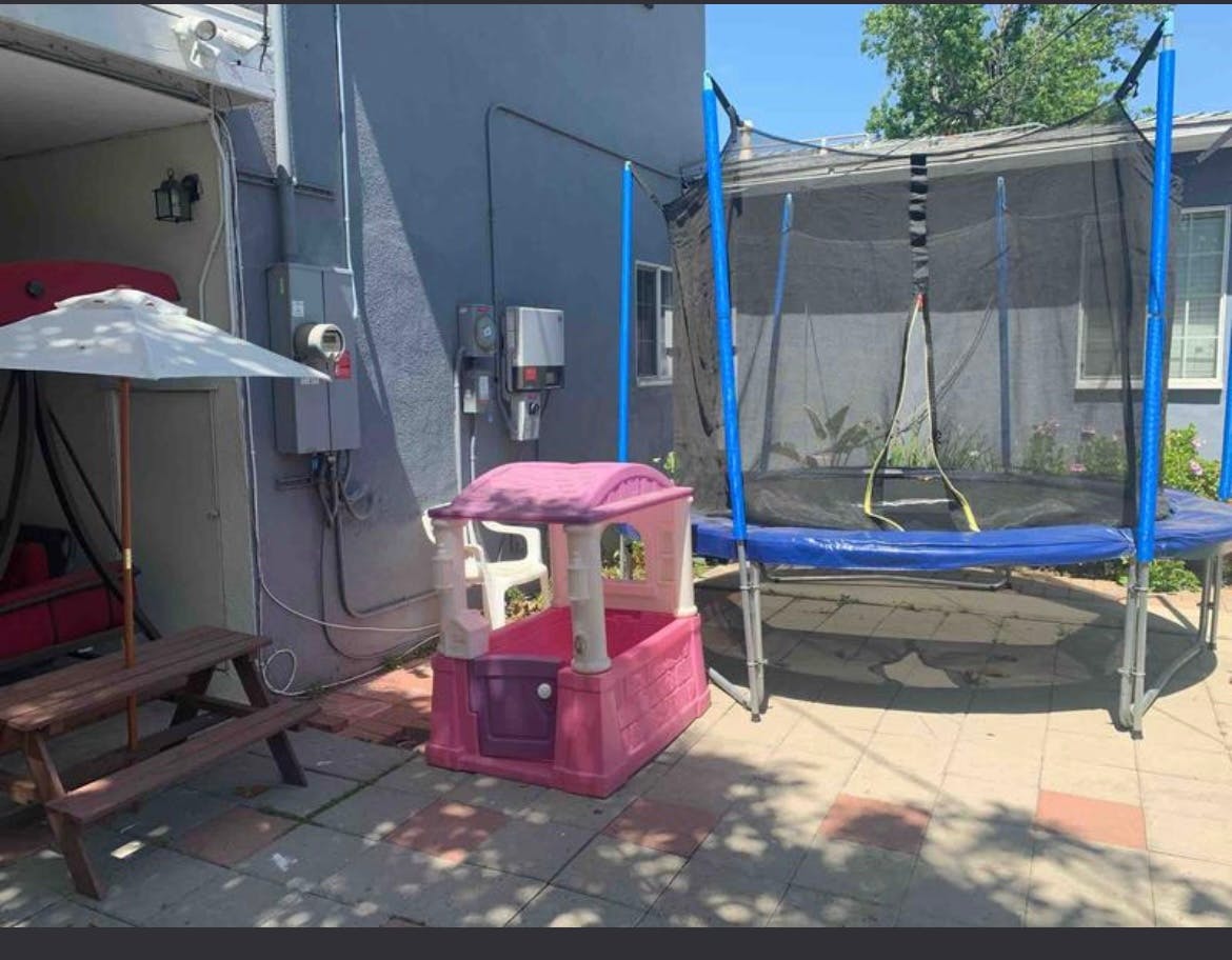 Trampoline, playhouse, and picnic table with umbrella