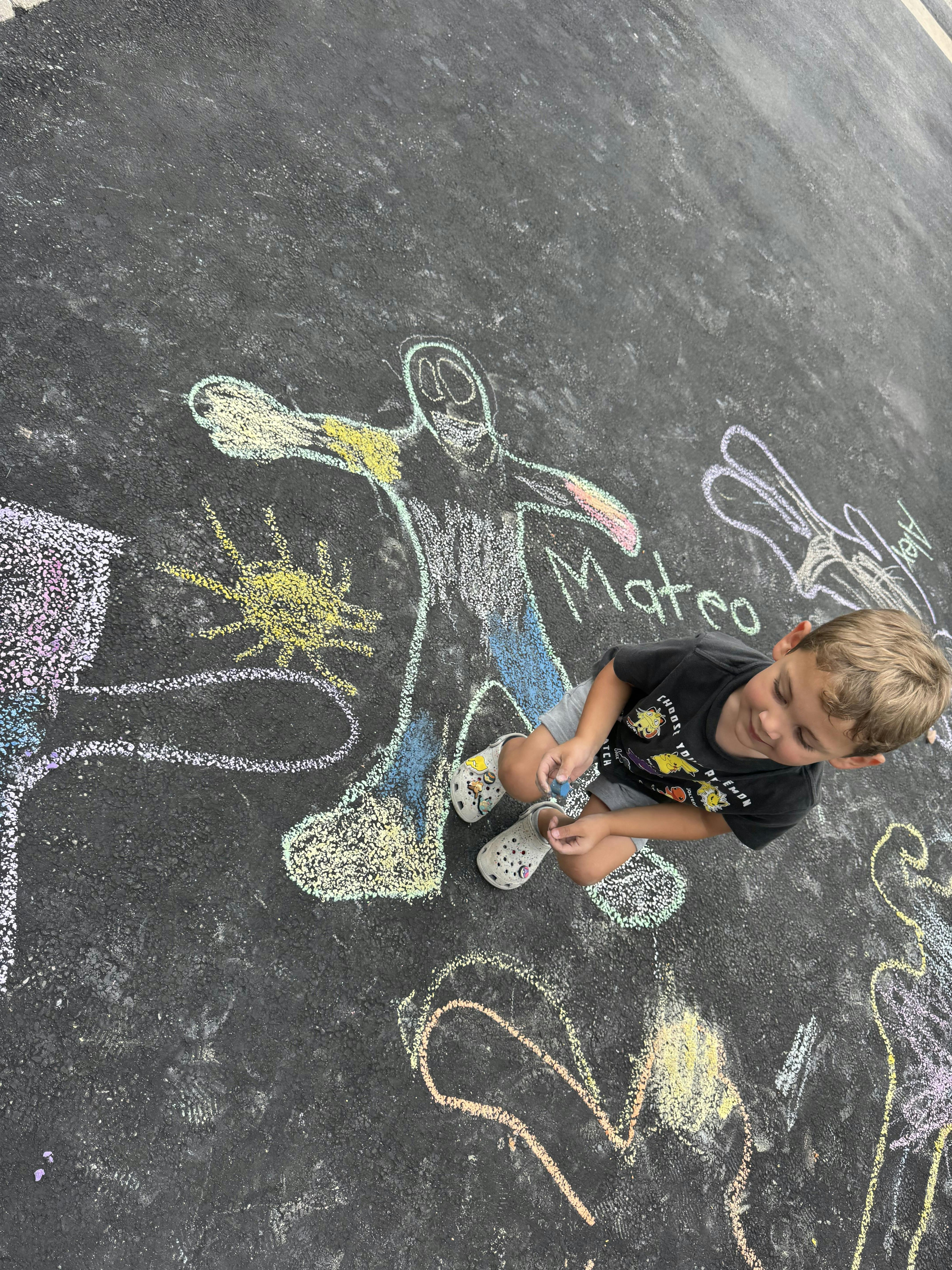 Child drawing with chalk on pavement