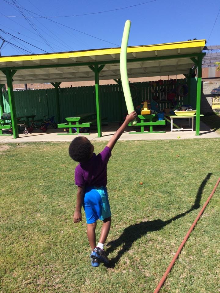 Child holding a long green balloon in the air