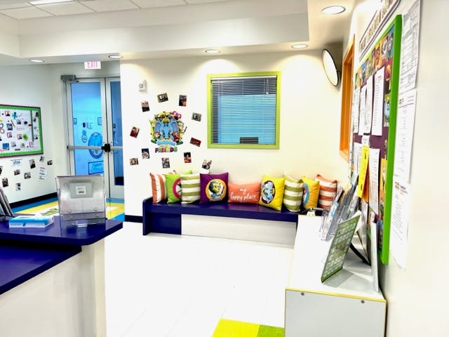Waiting room with a blue bench, colorful pillows, and bulletin boards