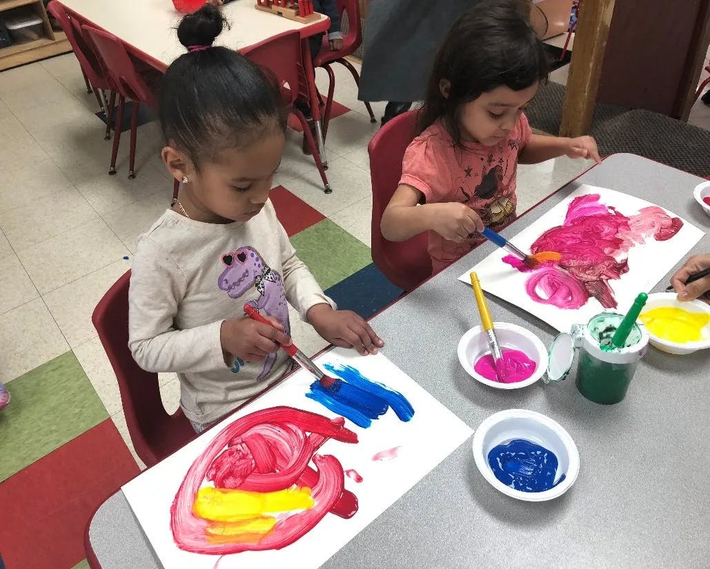 Two children painting at a table