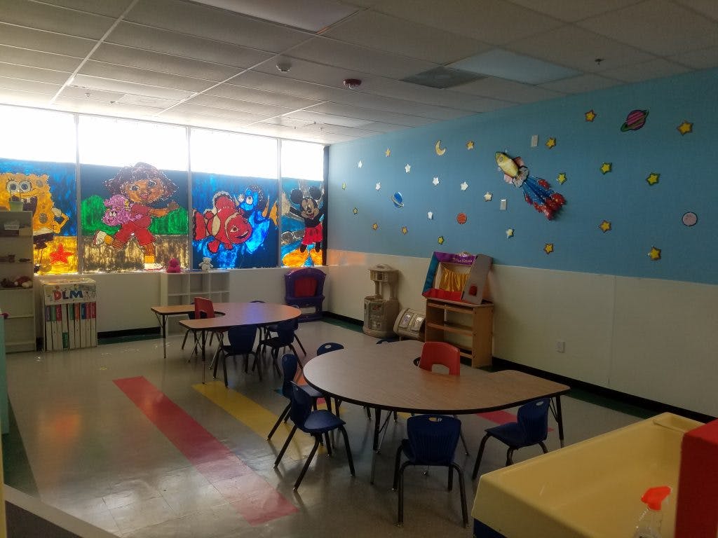 Empty classroom with small tables and chairs, decorated walls