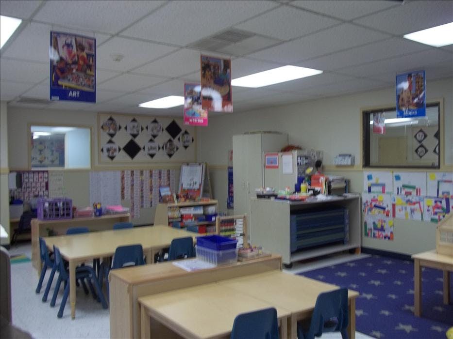 Empty classroom with small wooden tables and blue chairs