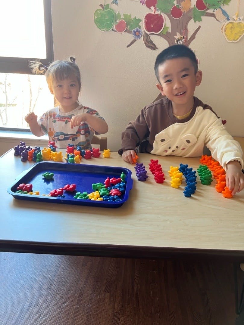 Two children playing with colorful bear counters at a table