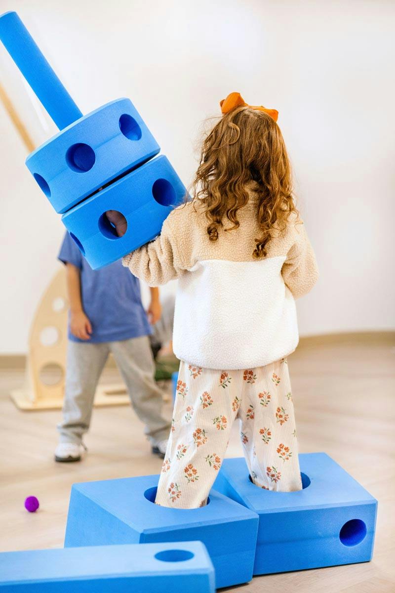 Two children playing with large blue foam construction blocks