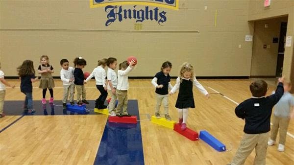 Children walking on balance beams in a gym