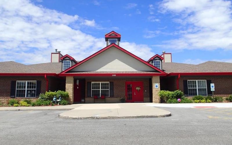 Front exterior of a single-story brick building with red trim and red double doors