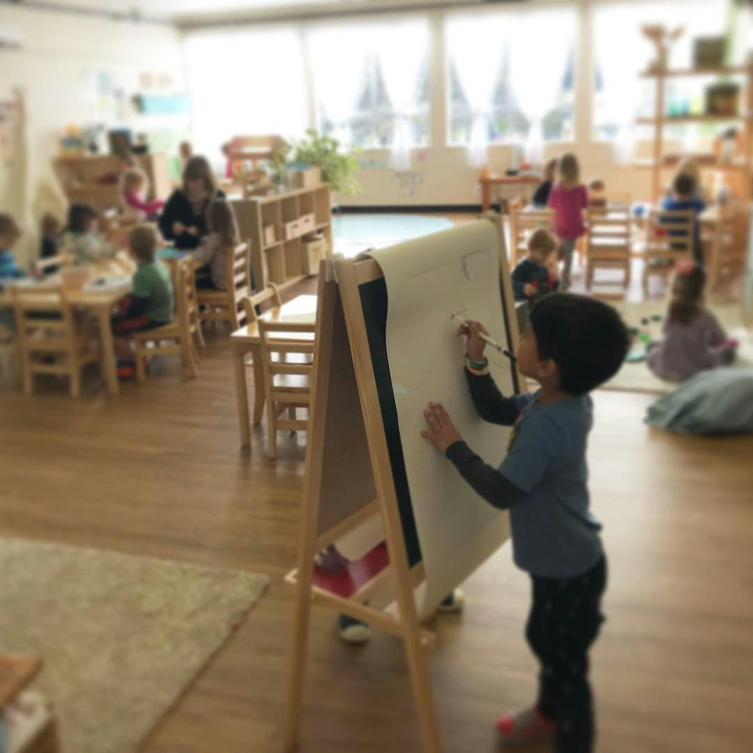 Child drawing on an easel in a classroom