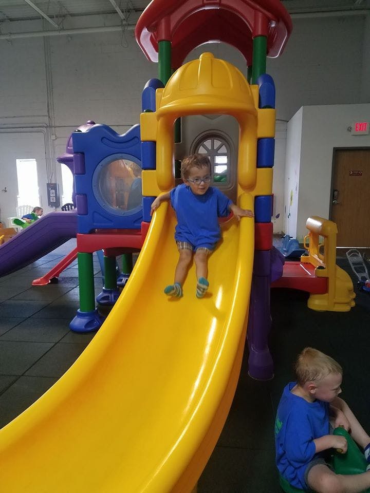Child in blue shirt on a yellow slide