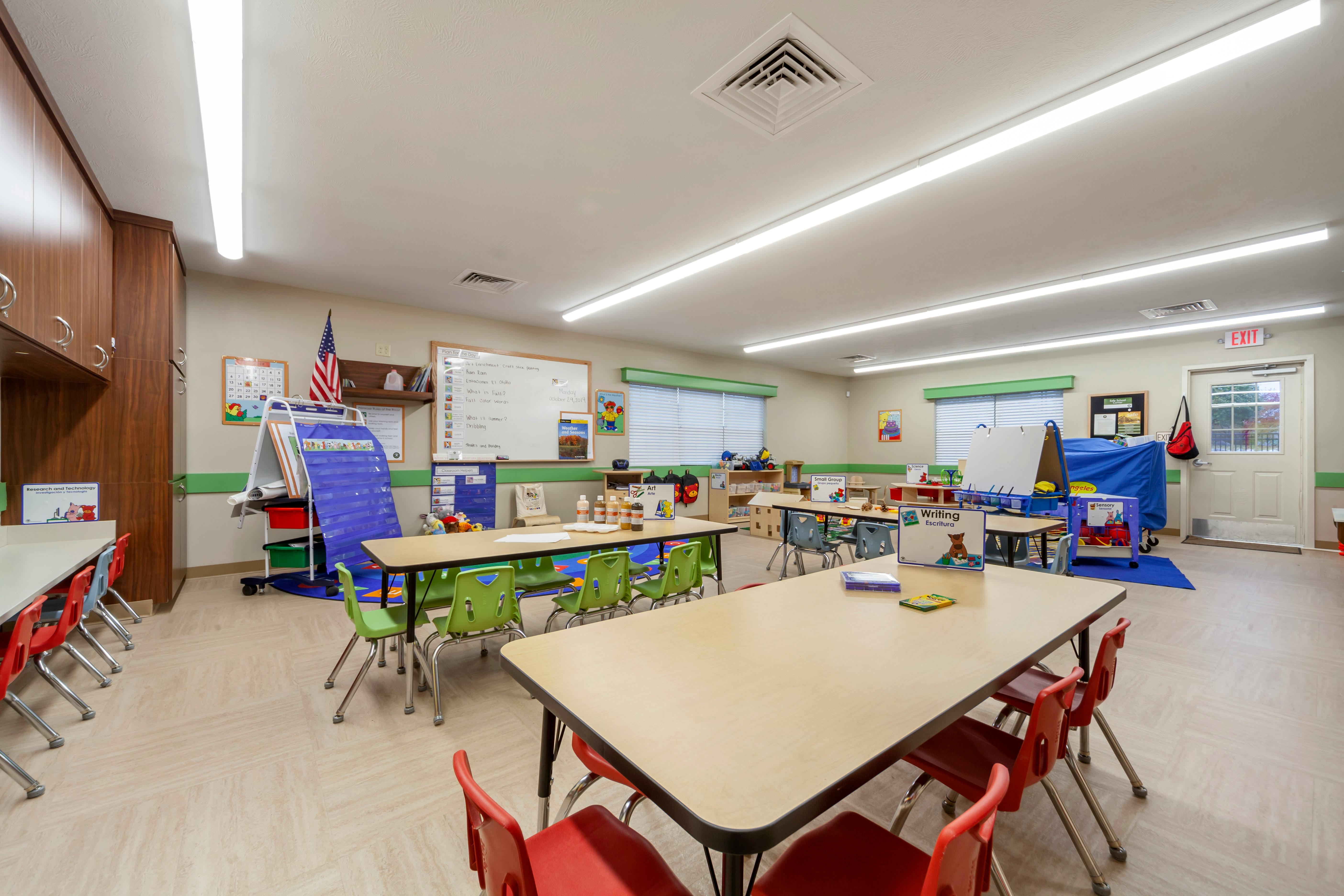 Empty classroom with tables, chairs, and learning materials