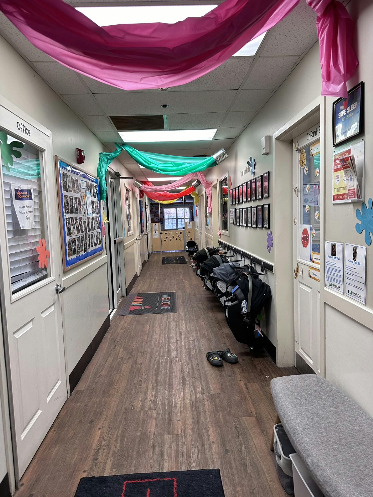 Hallway in a childcare center with car seats on hooks and colorful decorations