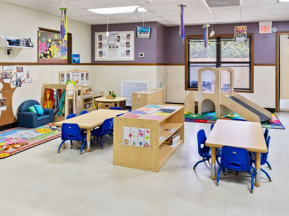 Children's classroom with small tables, chairs, and play structures