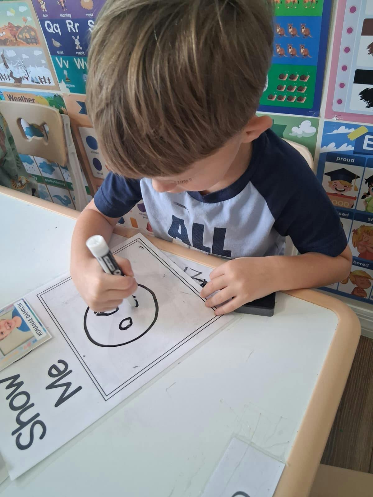 Child drawing on a worksheet at a desk in a classroom