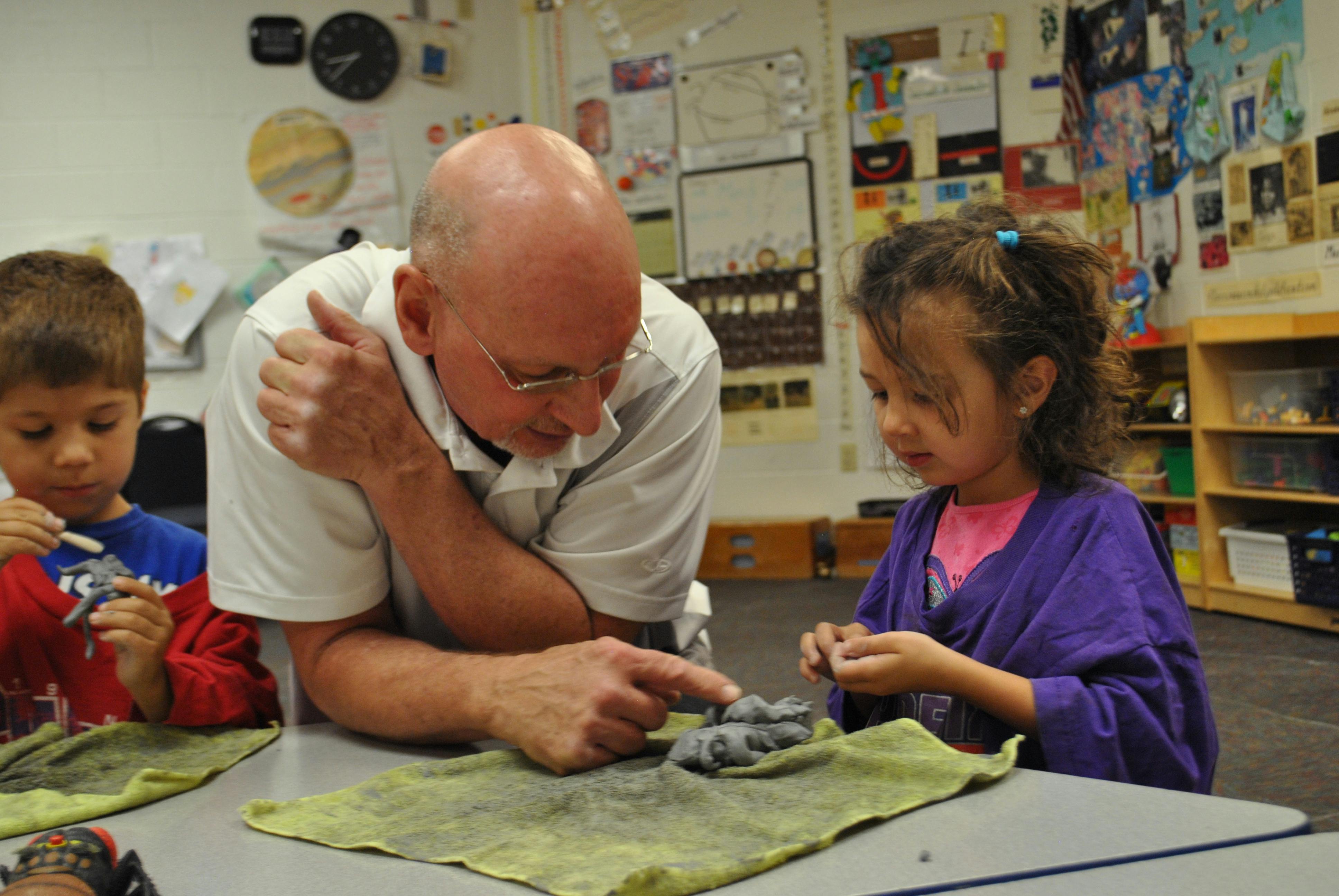 Adult and two children working with clay at a table