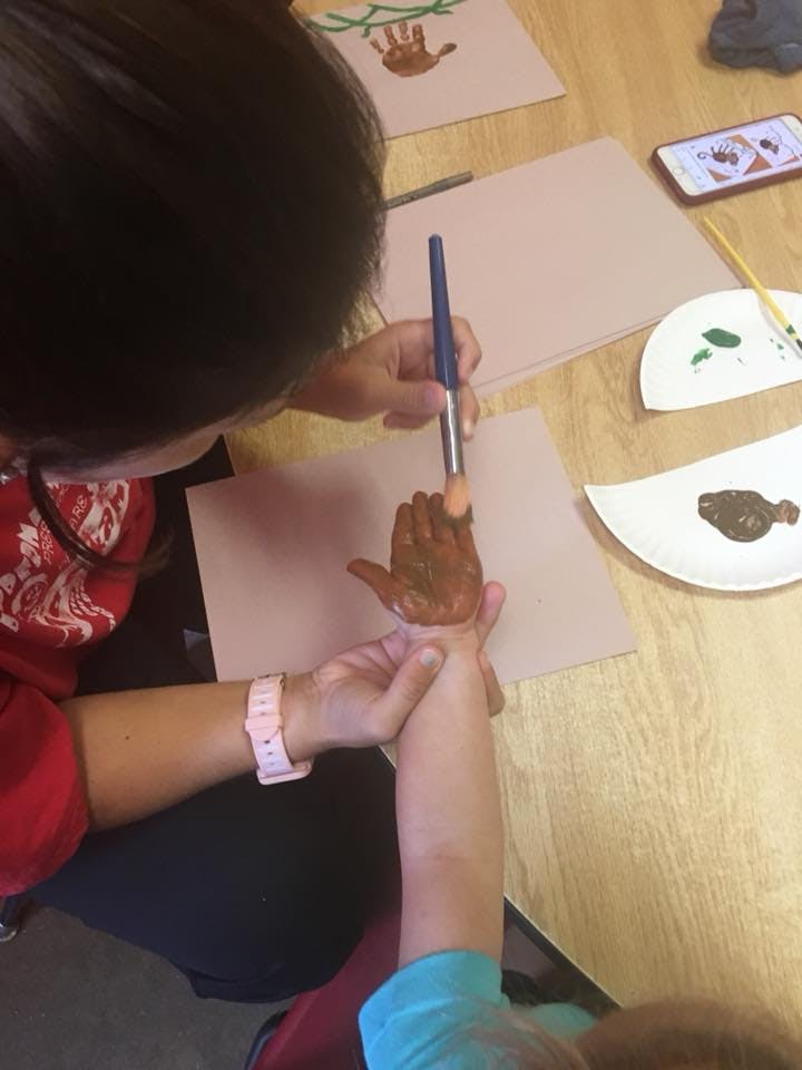 Person painting a child's hand with a brush
