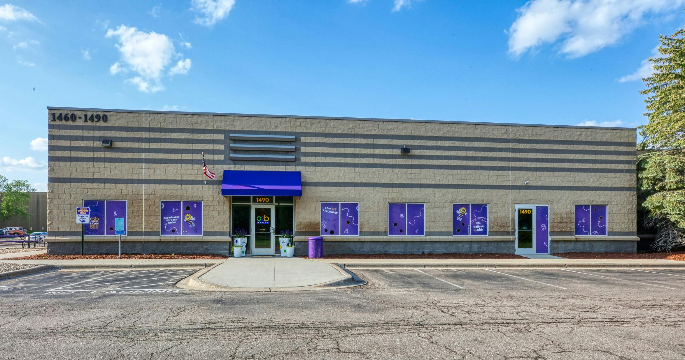 Exterior of a tan building with purple windows, blue awning, and a sign for "o2b kids"