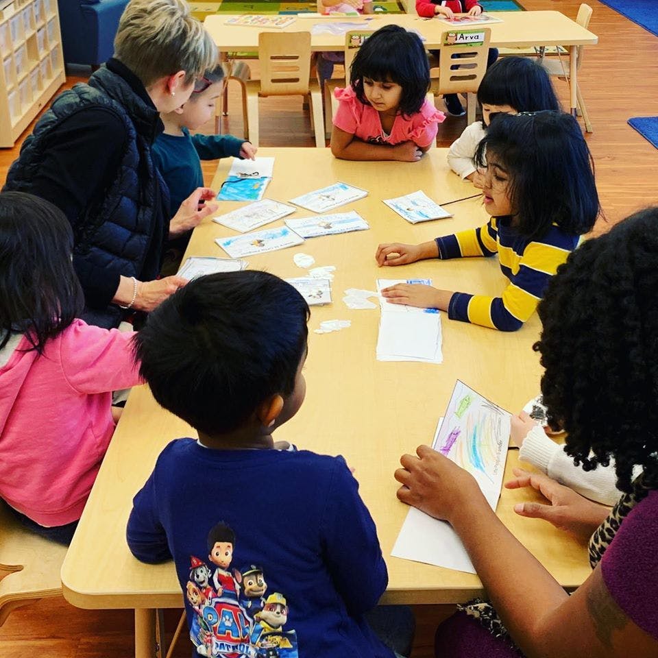 Adult and children sitting around a table with papers
