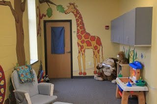 Child's room with giraffe mural, chair, and toys