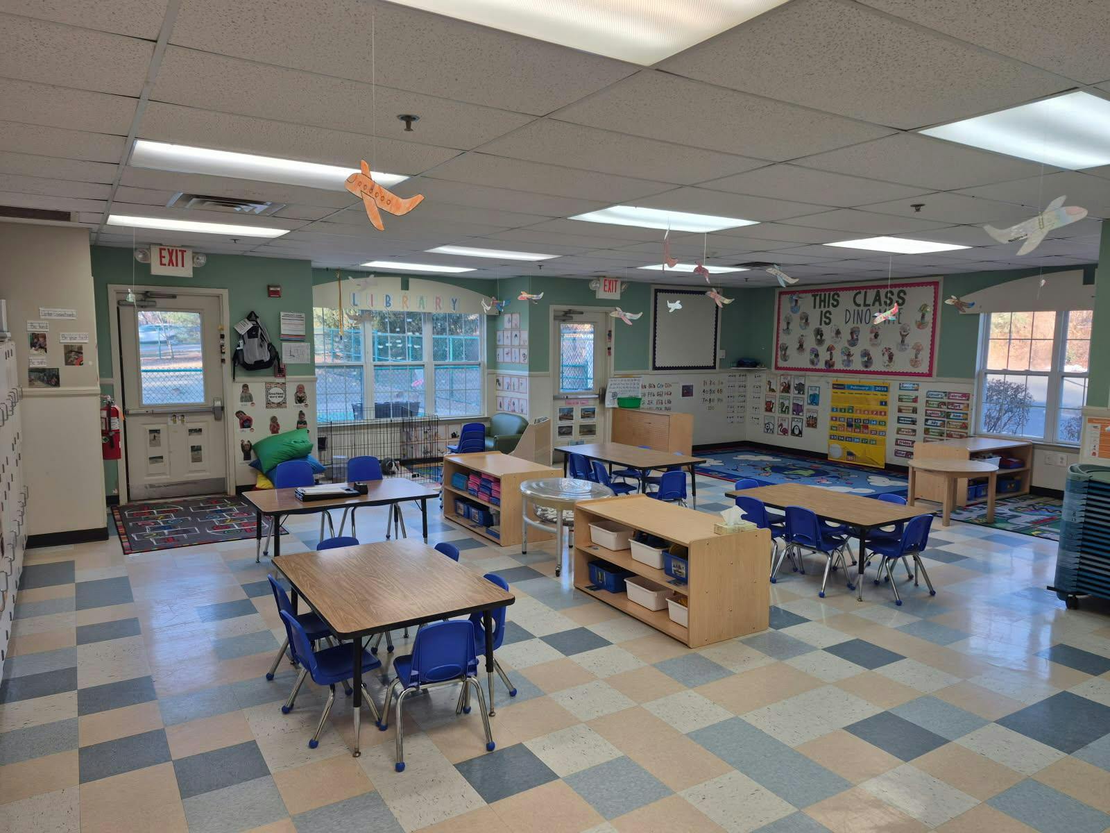 Empty classroom with small tables and chairs, and decorations on the walls