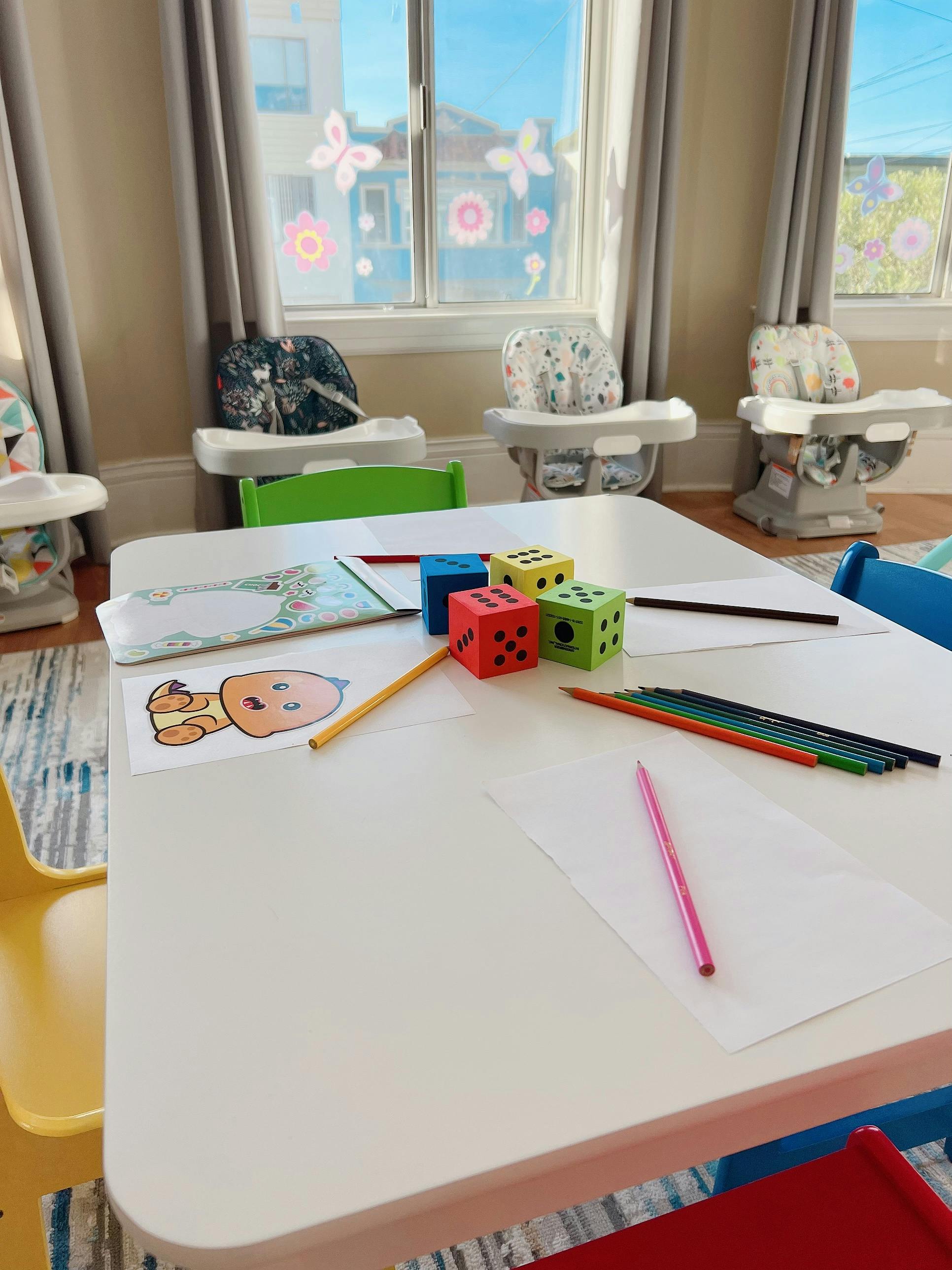 Table with drawing supplies, including paper, colored pencils, and dice