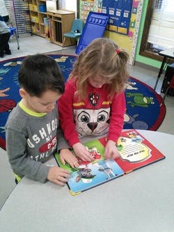 Two children looking at a book together