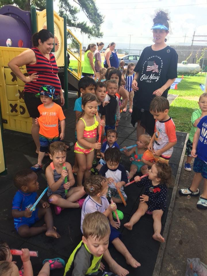 Adults and children gathered outdoors, some holding toys
