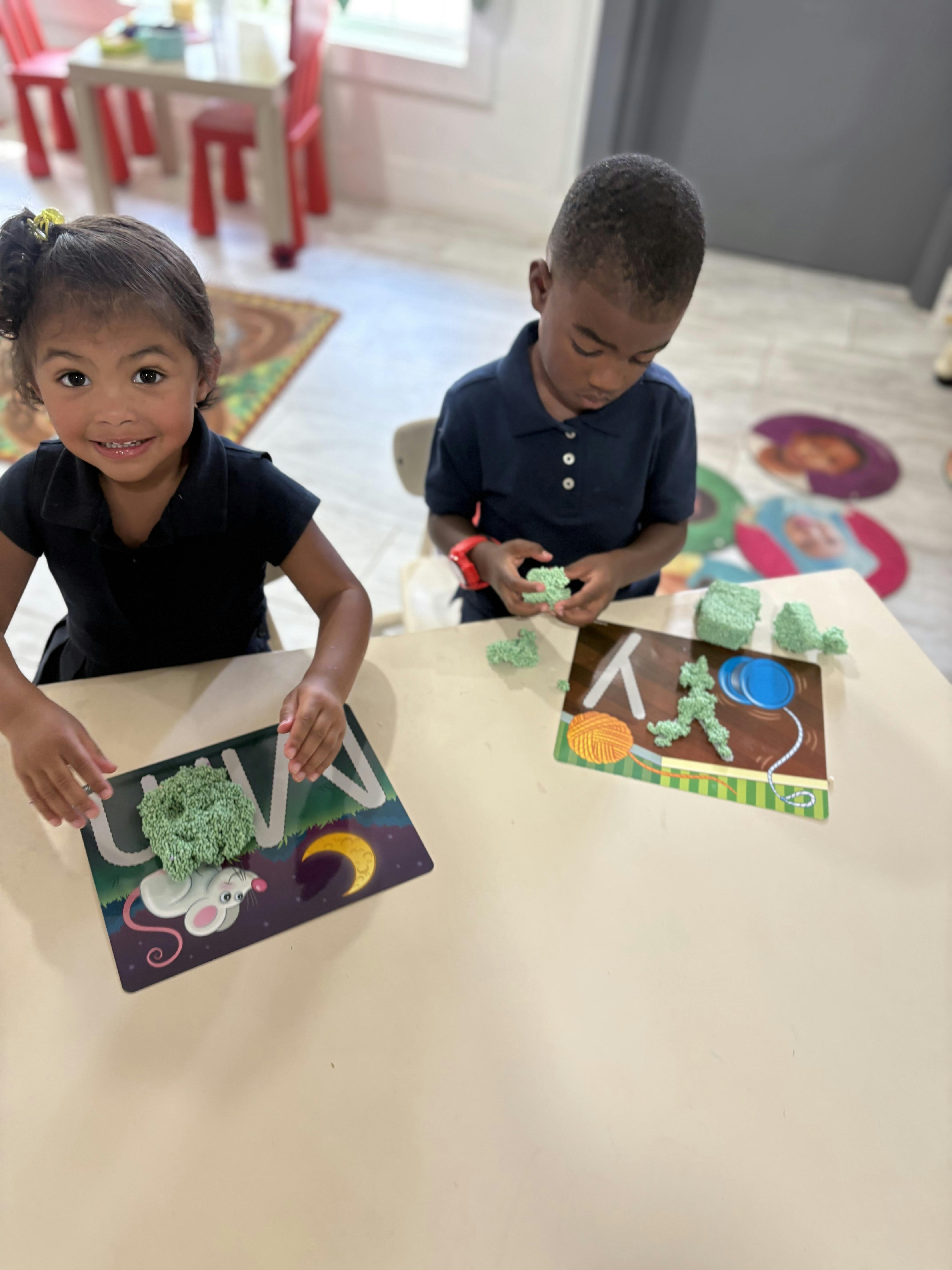 Two children playing with textured green modeling compound on a tabletop
