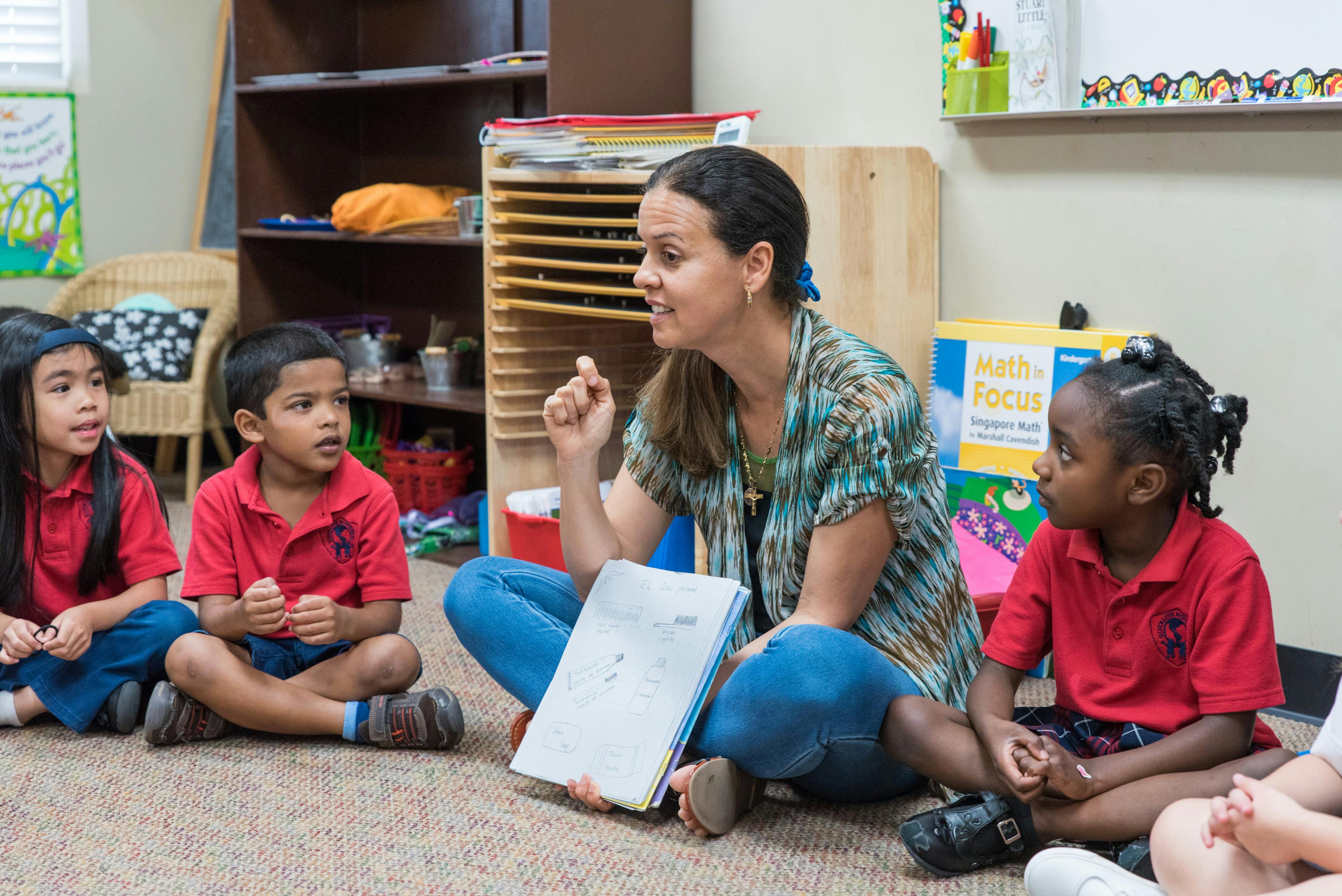 Adult and three children sitting on floor in classroom