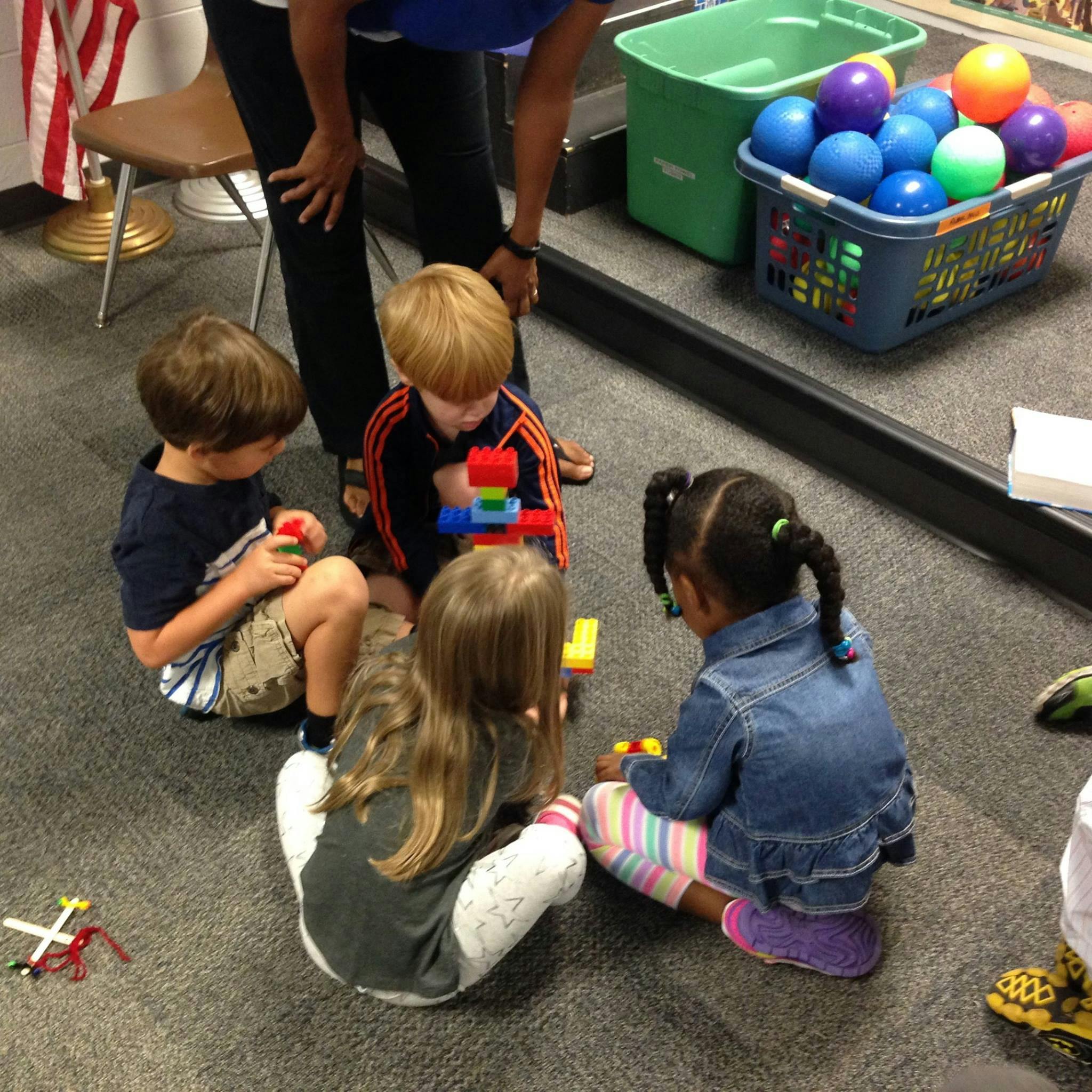 Four children playing with building blocks on the floor