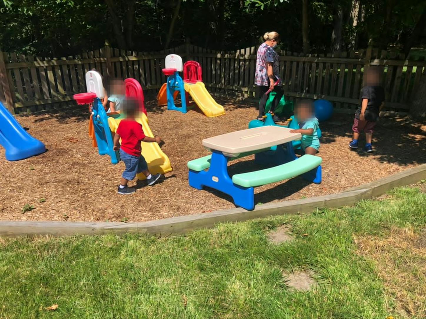 Children playing with plastic slides and a table in a playground