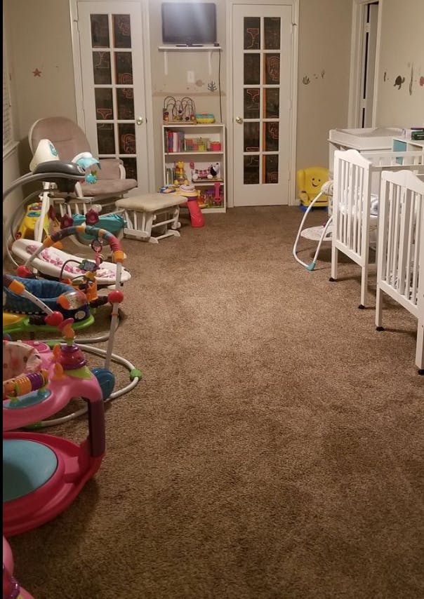 Room with baby swings, cribs, and a bookshelf