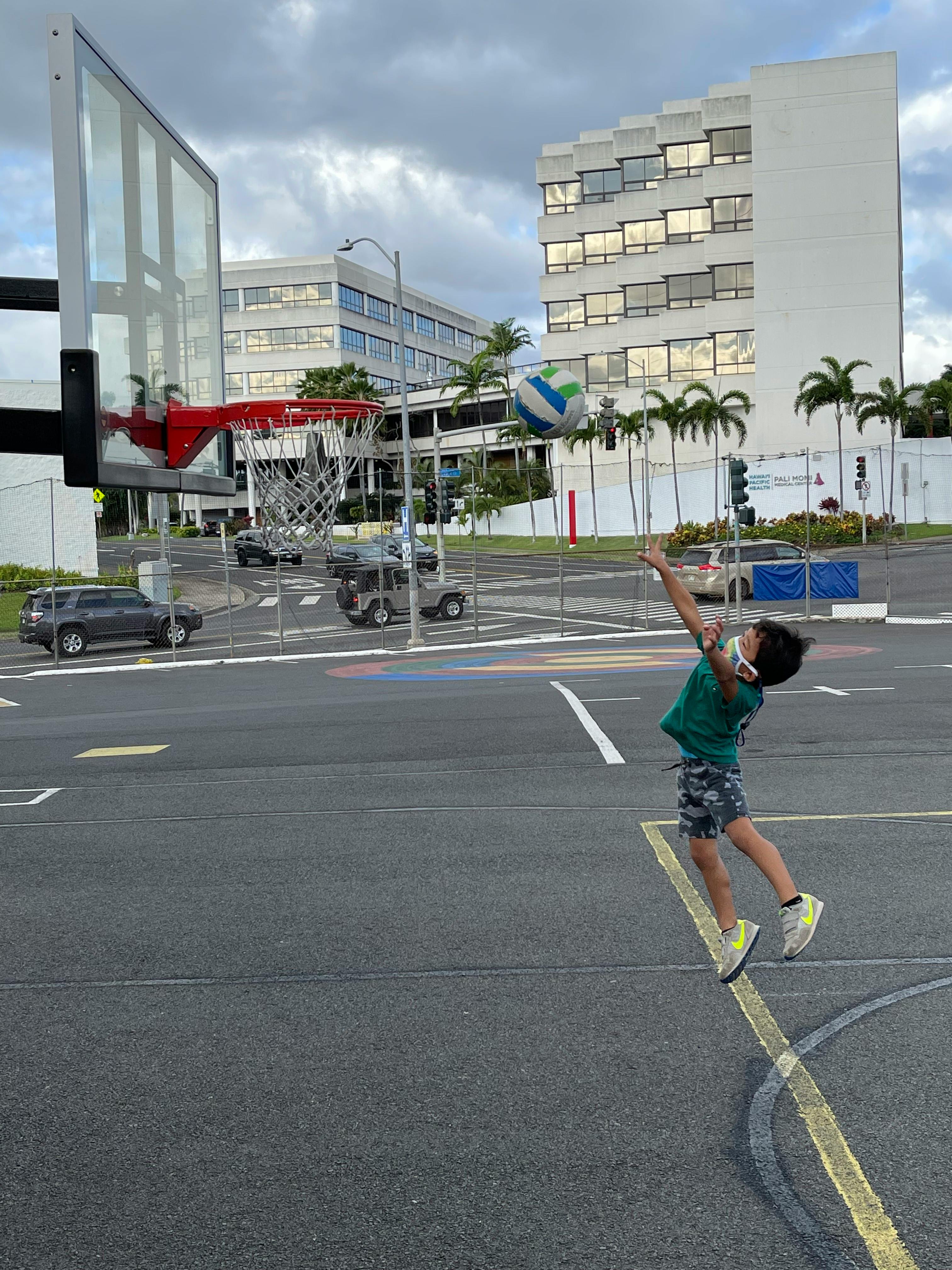 Child playing basketball, shooting a ball towards a hoop