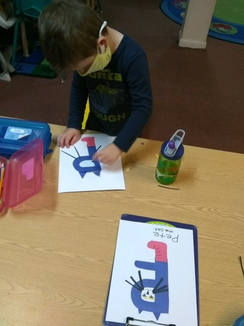 Child in a mask working on a craft project at a table