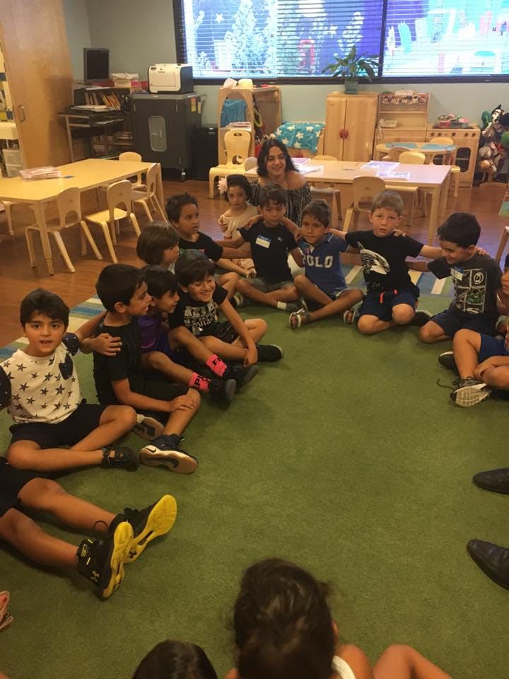 Adult and children sitting in a circle on the floor in a classroom