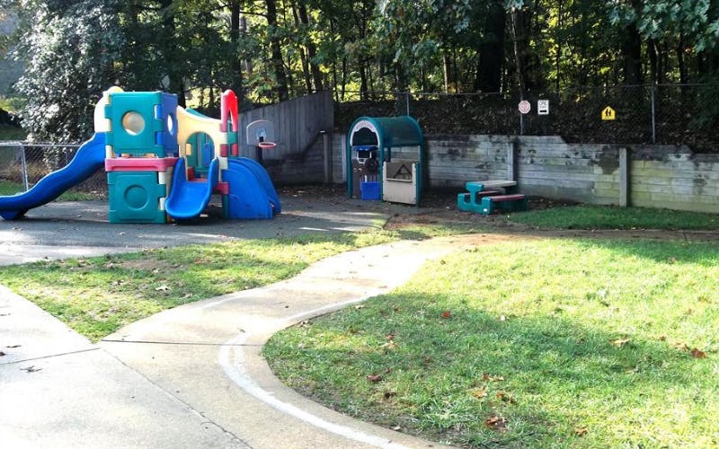 A colorful plastic playground with slides next to a small picnic table