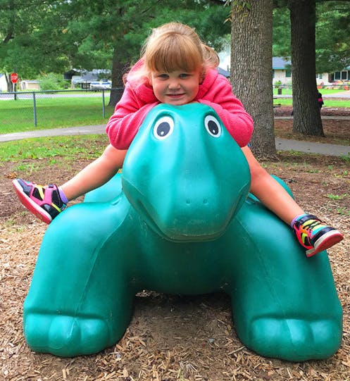 Child on a green turtle-shaped playground spring rider