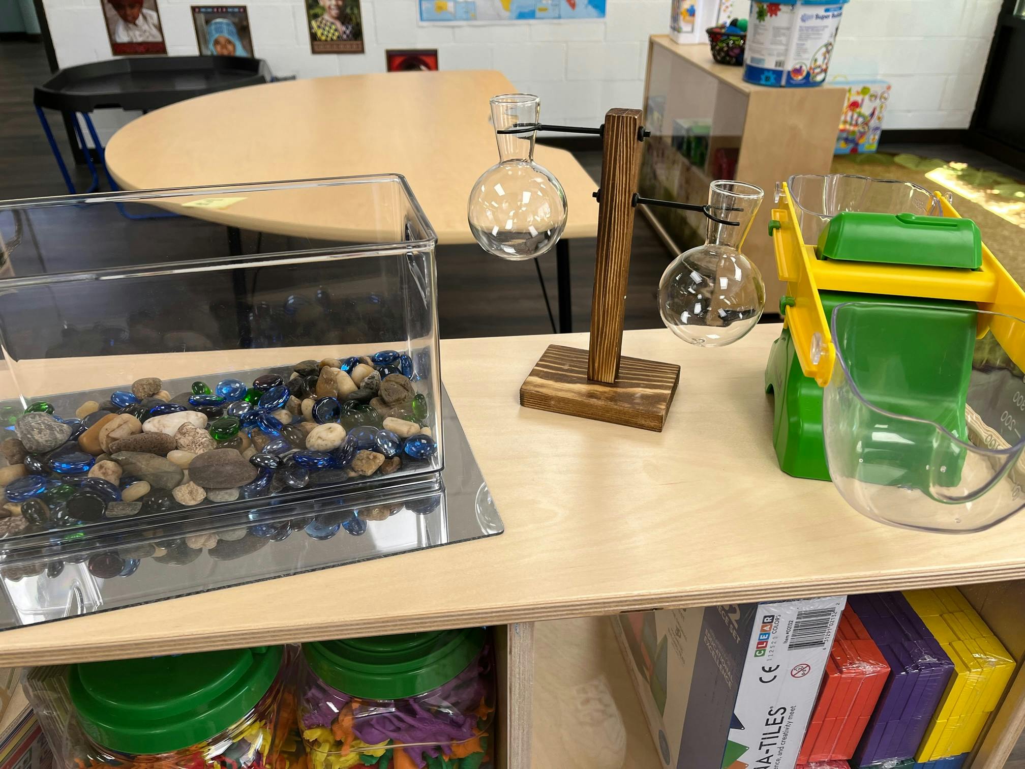 Clear container with rocks and glass beads next to glass bulbs on a stand