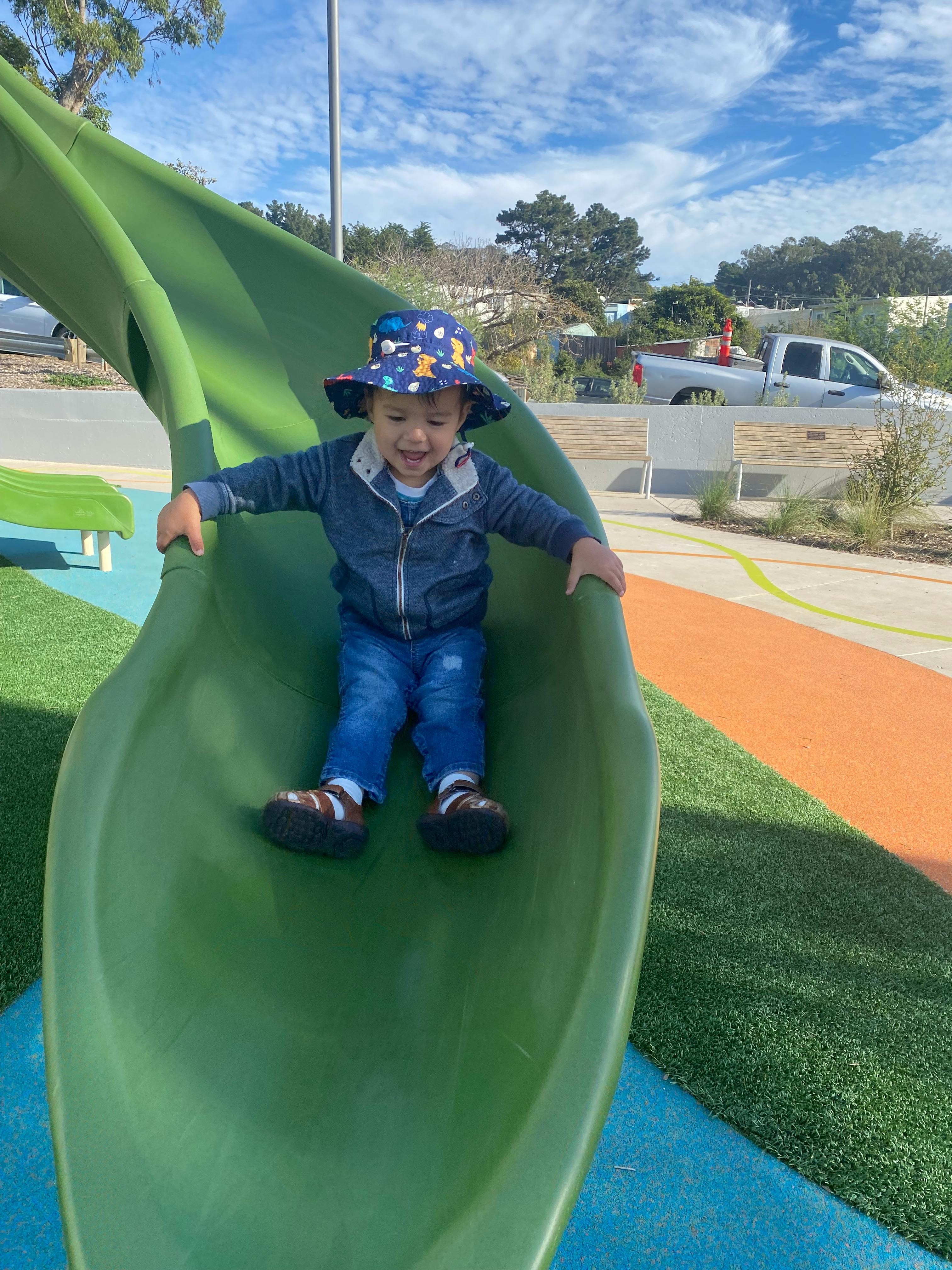Child in a hat on a green slide